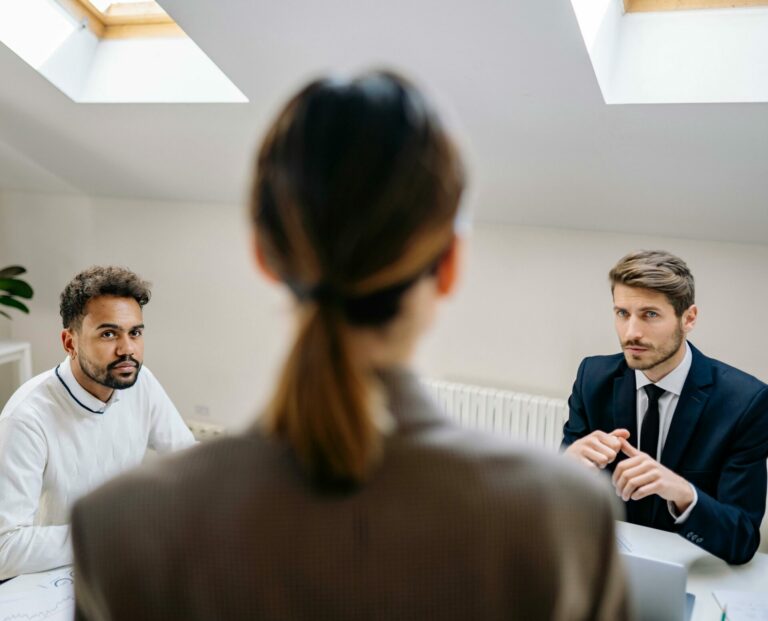 A professional business meeting involving three adults in a modern office setting.
