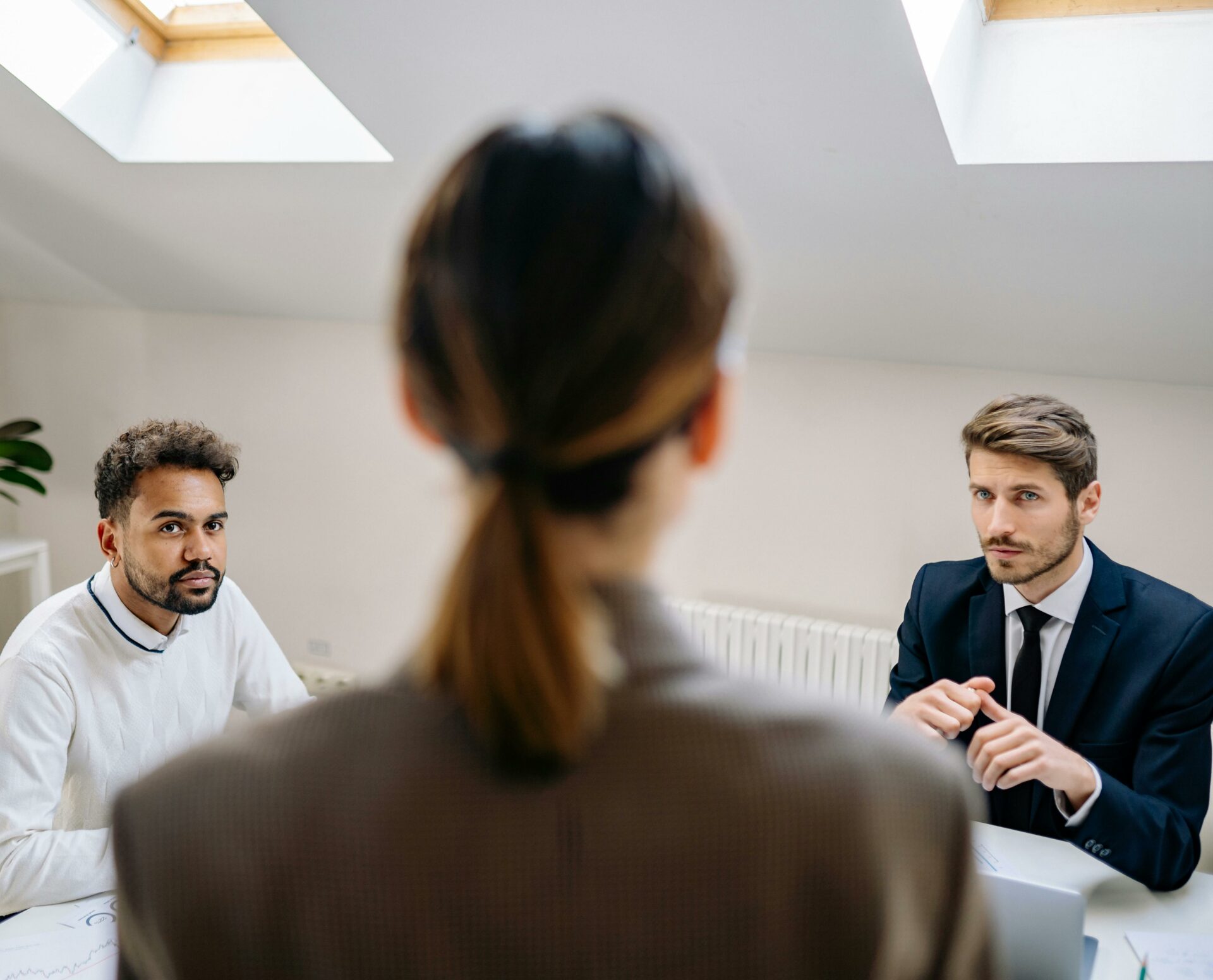 A professional business meeting involving three adults in a modern office setting.